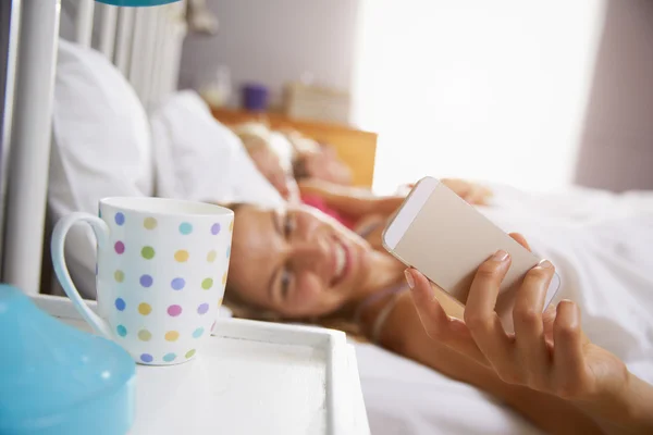 Mãe chega para verificar o telefone móvel — Fotografia de Stock