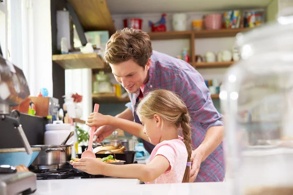 Filha ajudando o pai a cozinhar a refeição — Fotografia de Stock