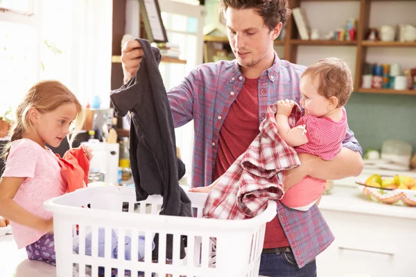 Pai e filhos ordenando lavanderia — Fotografia de Stock