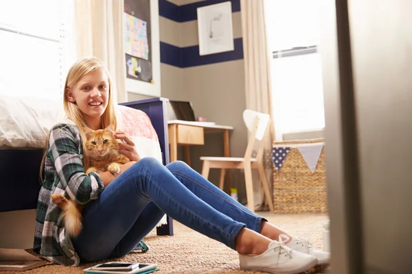 Chica sosteniendo gato mascota en su dormitorio — Foto de Stock
