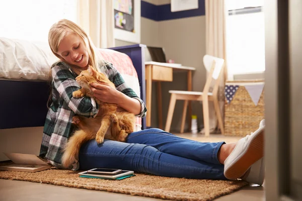 Menina segurando gato de estimação em seu quarto — Fotografia de Stock