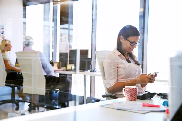 Vrouw met behulp van slimme telefoon in een kantoor — Stockfoto
