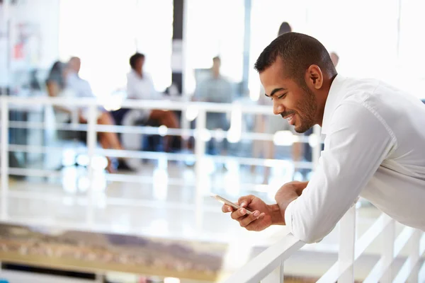 Uomo che utilizza il telefono cellulare in ufficio — Foto Stock