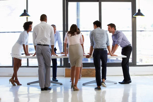 Colleagues standing around a conference table — Stock Photo, Image