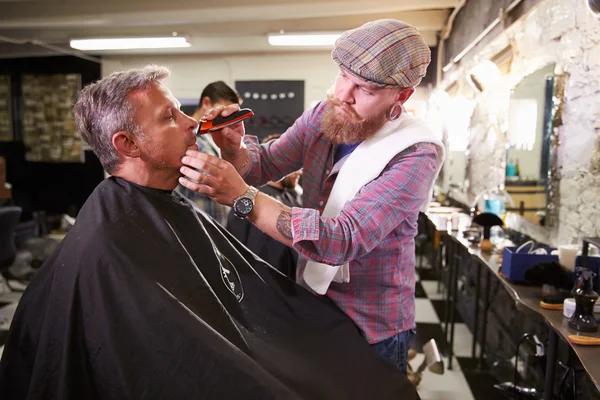 ショップでクライアントのひげそりを与える男性の床屋 — ストック写真