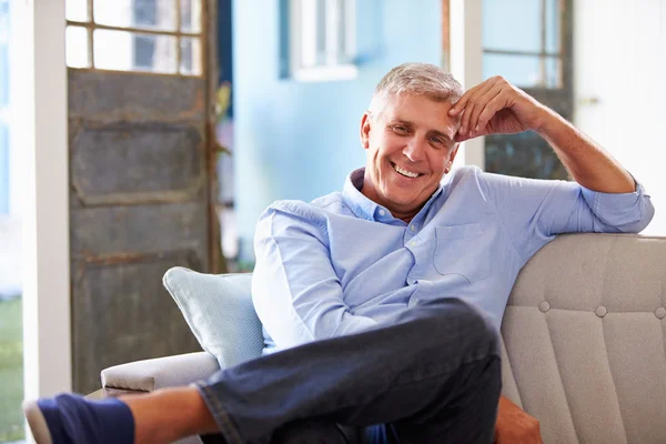 Sorridente uomo maturo seduto sul divano — Foto Stock