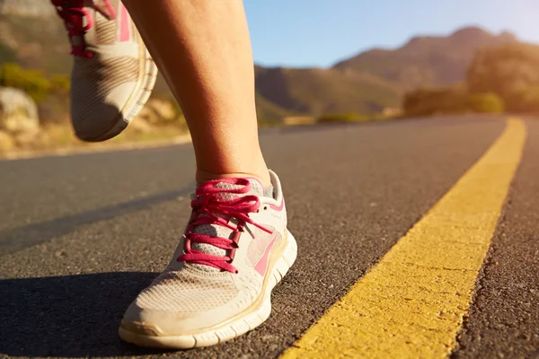 Vrouwelijke jogger draait op een lege weg — Stockfoto