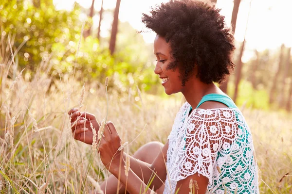 Sorrindo jovem mulher sentada no campo — Fotografia de Stock