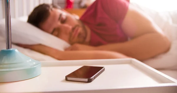 Homem dormindo usando alarme no telefone móvel — Fotografia de Stock