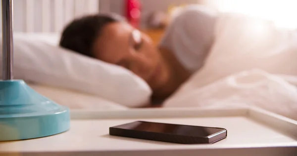 Mujer durmiendo en la cama usando alarma en el teléfono móvil — Foto de Stock