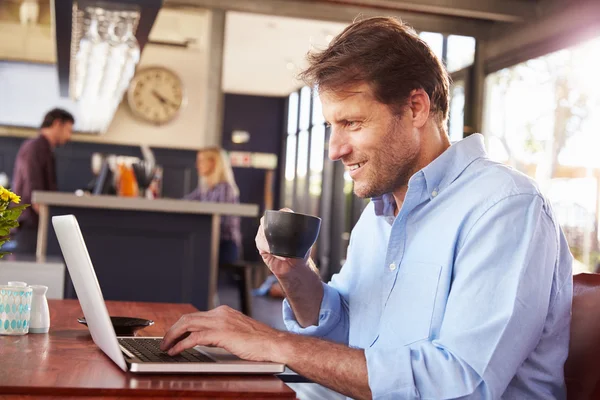 Hombre trabajando en el ordenador portátil en una cafetería — Foto de Stock