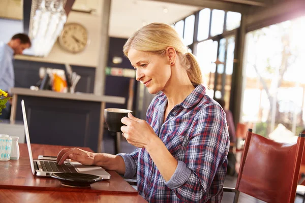 Mujer usando en el ordenador portátil en una cafetería — Foto de Stock