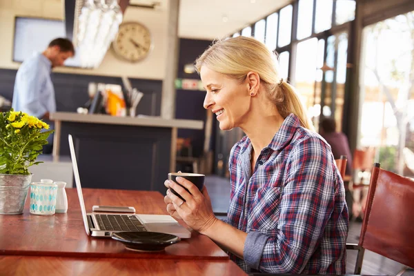 Mujer usando en el ordenador portátil en una cafetería — Foto de Stock