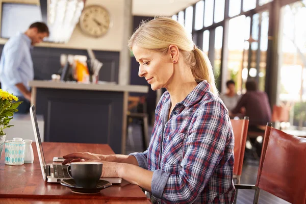 Donna che usa il portatile in una caffetteria — Foto Stock