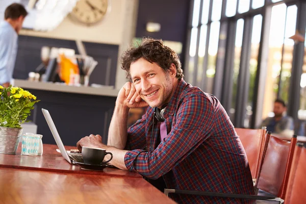 Hombre trabajando en la computadora en la cafetería — Foto de Stock