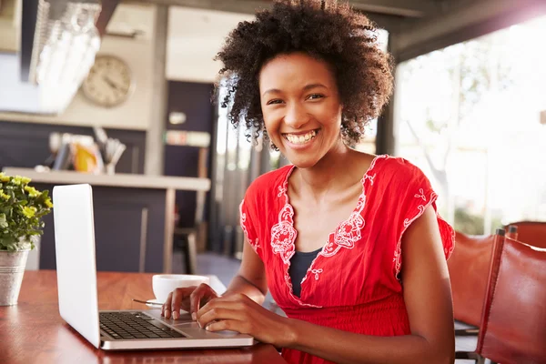 Vrouw met behulp van een laptop in een coffeeshop — Stockfoto