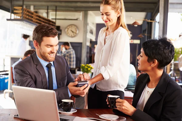 Empresario haciendo pago con tarjeta de crédito en un café — Foto de Stock