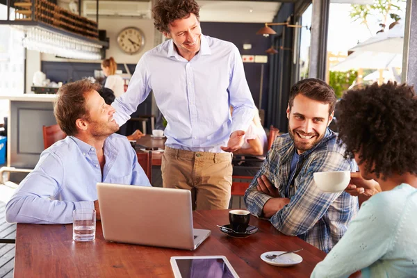 Restaurant manager talking to customers at their table — Stock Photo, Image