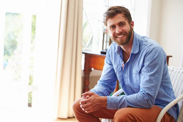 Lächelnder Mann sitzt in einem Zimmer — Stockfoto