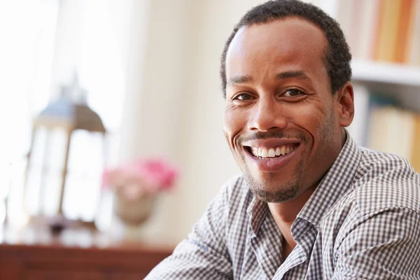 Homme souriant assis dans une pièce — Photo