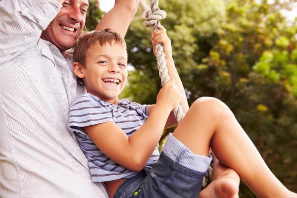 Father swinging with son at a playground — Stock Photo, Image