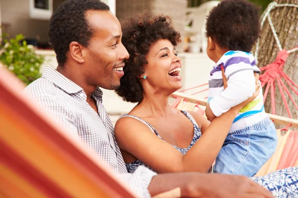 Pareja feliz con niño sentado en una hamaca —  Fotos de Stock