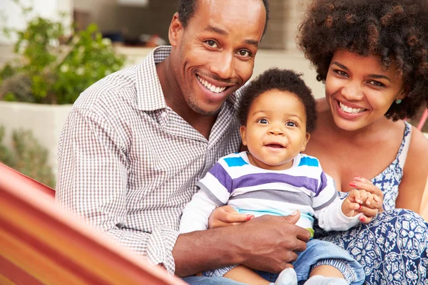 Pareja feliz con niño sentado en una hamaca — Foto de Stock