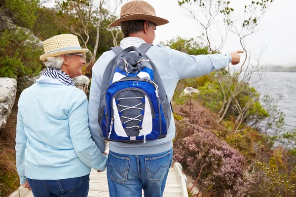 Casal sênior caminhando junto a um lago — Fotografia de Stock