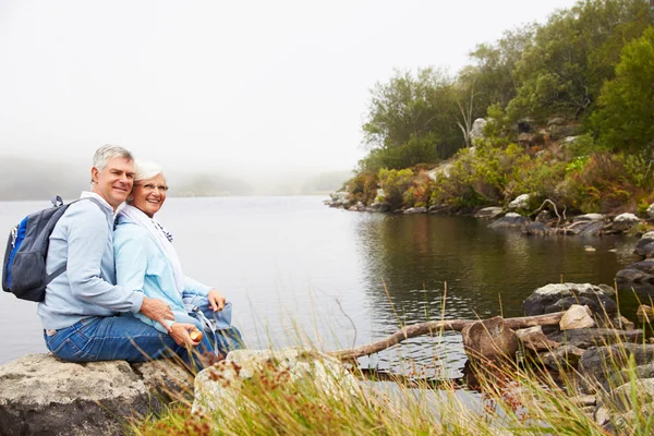 Üst düzey çift birlikte bir göl kenarında oturan — Stok fotoğraf