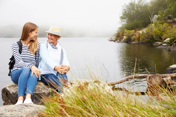 Mother and young daughter relaxing by a lake — Stock Photo, Image