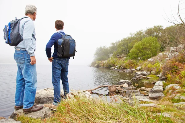Bir göl kenarında duran baba ve yetişkin oğlu — Stok fotoğraf