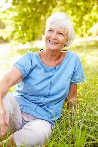 Starší žena sedící na trávě — Stock fotografie