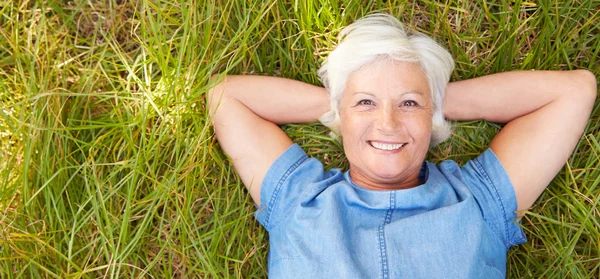 Senior vrouw liggen op gras — Stockfoto