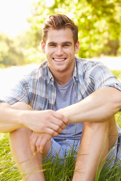 Mladý muž seděl na trávě — Stock fotografie
