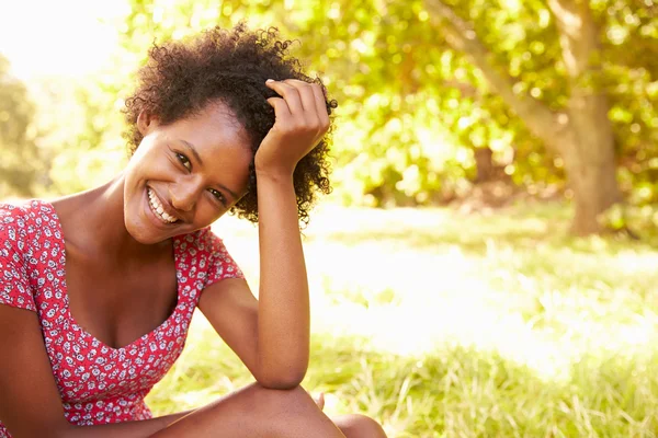 Jeune femme assise sur l'herbe relaxante — Photo