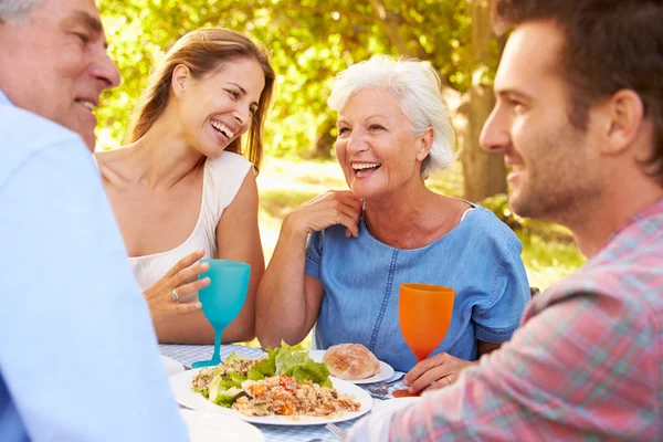 Un adulto mayor y una pareja joven comiendo juntos — Foto de Stock