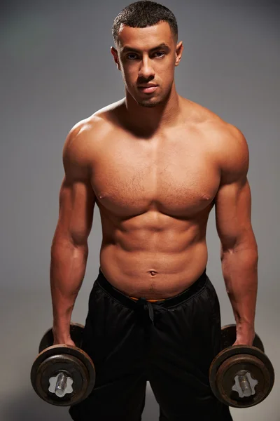 Male bodybuilder holding dumbbells — Stock Photo, Image