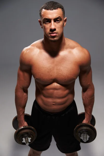 Male bodybuilder holding dumbbells — Stock Photo, Image