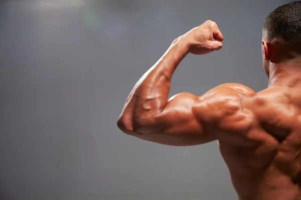 Male bodybuilder flexing bicep — Stock Photo, Image