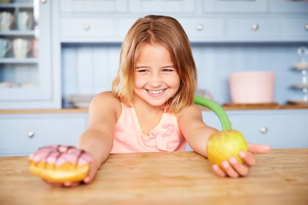 Chica elegir pasteles o manzana para merienda —  Fotos de Stock