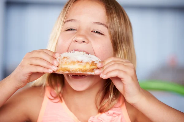 Chica sentada comiendo rosquilla azucarada — Foto de Stock