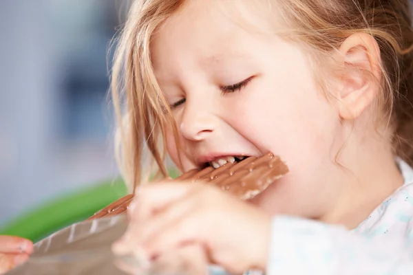 Menina comer bar de chocolate — Fotografia de Stock