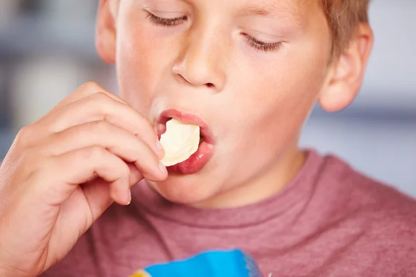 Хлопчик їсть пакет картопляних чіпсів — стокове фото