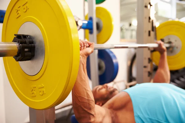 Banco de hombre presionando pesas en un gimnasio — Foto de Stock