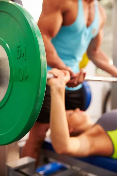 Woman lifting weights with trainer — Stockfoto