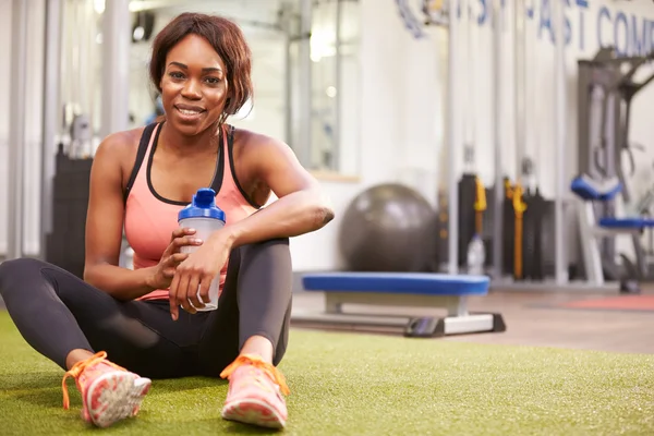 Jonge vrouw drinkwater in een sportschool — Stockfoto