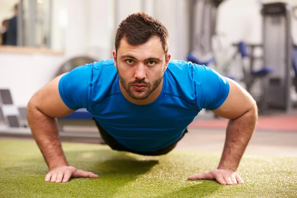 Hombre haciendo flexiones en un gimnasio — Foto de Stock