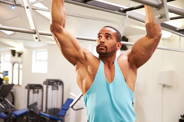 Man flexing muscles on monkey bars — Stock Photo, Image