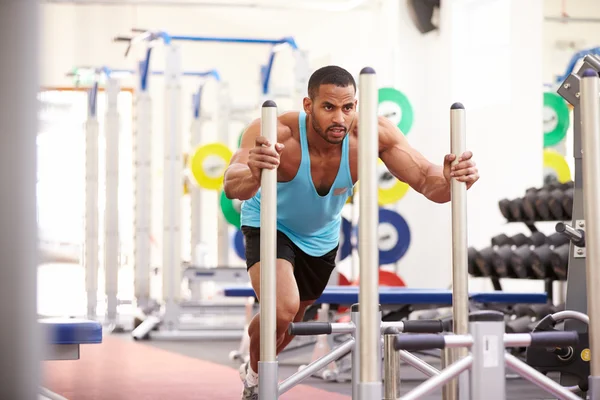 Hombre musculoso haciendo ejercicio en un gimnasio — Foto de Stock