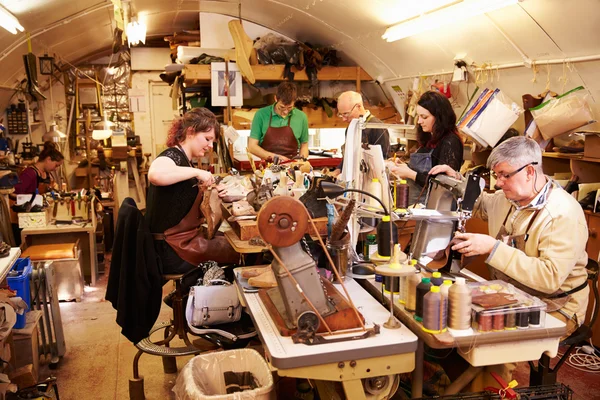 Para pembuat sepatu bekerja di bengkel yang sibuk, pandangan umum Stok Gambar Bebas Royalti